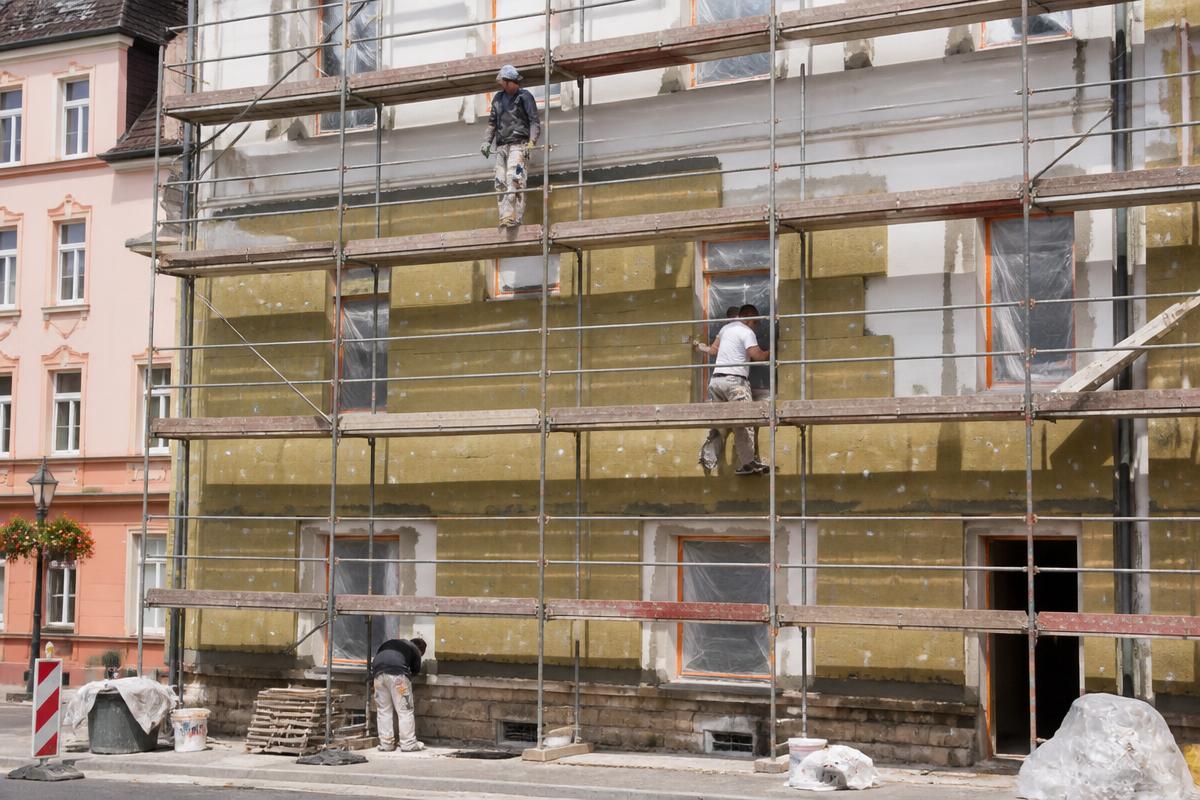 Radnici na skeli postavljaju toplinsku izolaciju na fasadu objekta